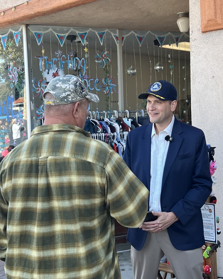 Bob Smith talking with a resident outside a shop on a main street